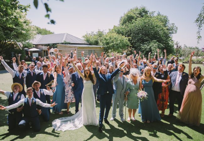 A wedding group cheering in a group photo