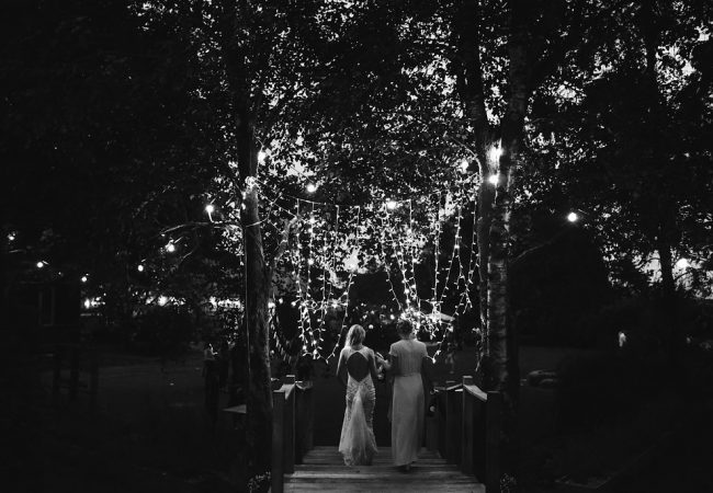 Black and white at night with fairy lights and people walking away from camera