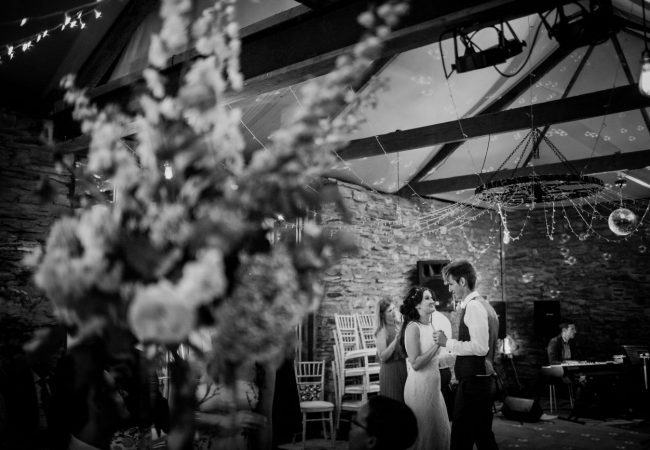 A couple dancing in balck and white with flowers in the foreground