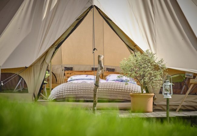 A front view of looking through a glamping tent doorway with visuals of a kingsize bed
